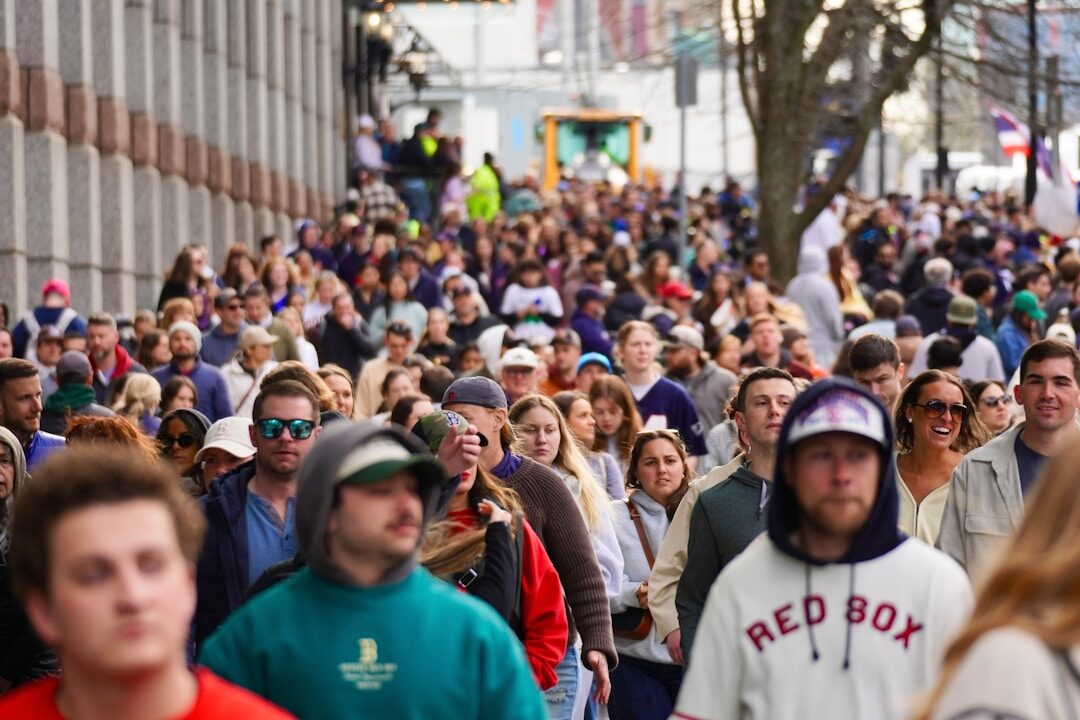 A large crowd of people walking down a city street.